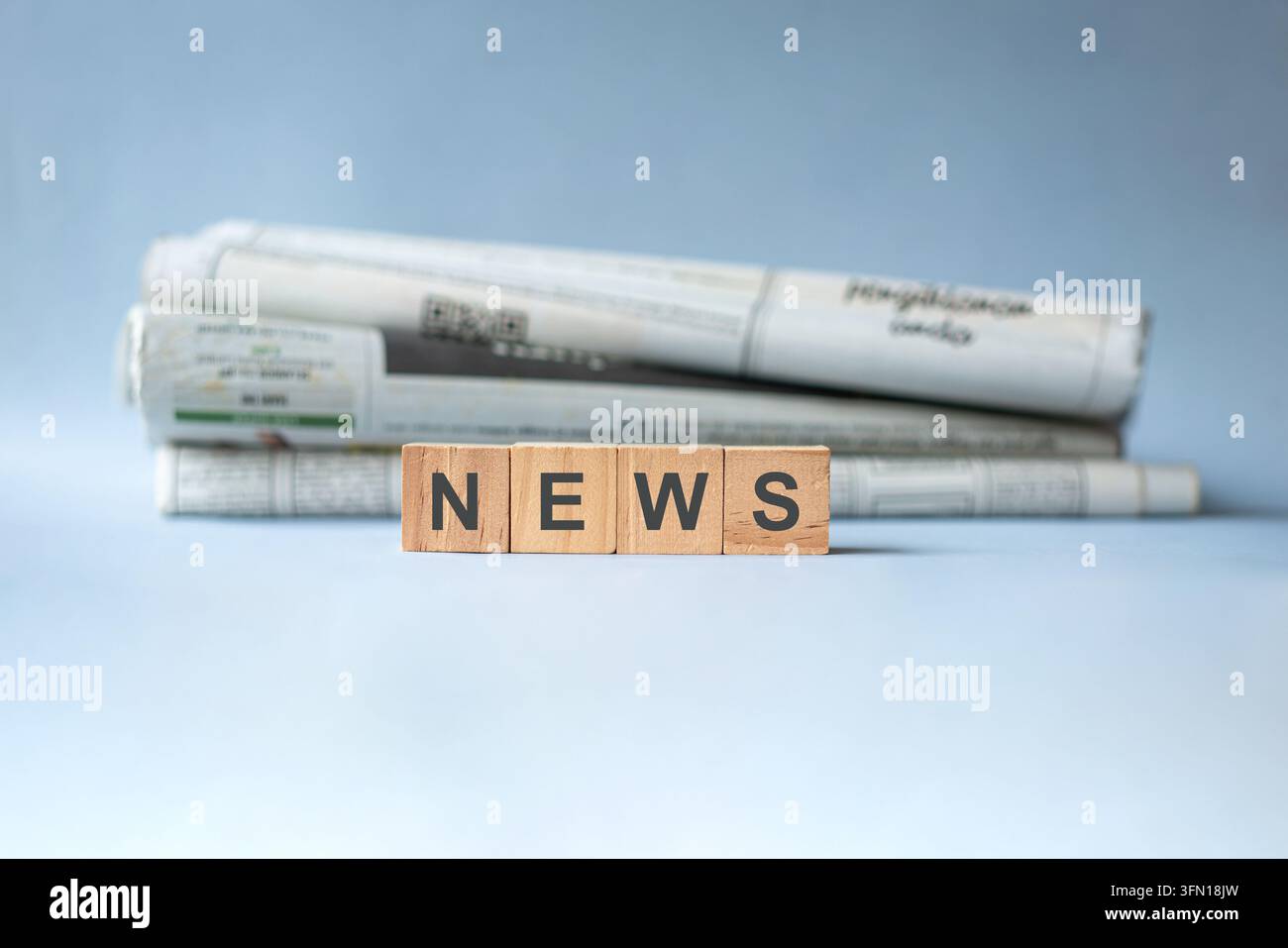 Notizie su blocchi di legno con giornali impilati sullo sfondo. Foto Stock