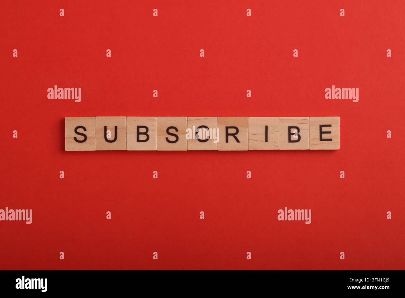Blocchi di lettere di legno che compongono la parola "subscribe" su uno sfondo rosso, rappresentanti contenuti online, marketing digitale, canali video, coinvolgimento sui social media Foto Stock