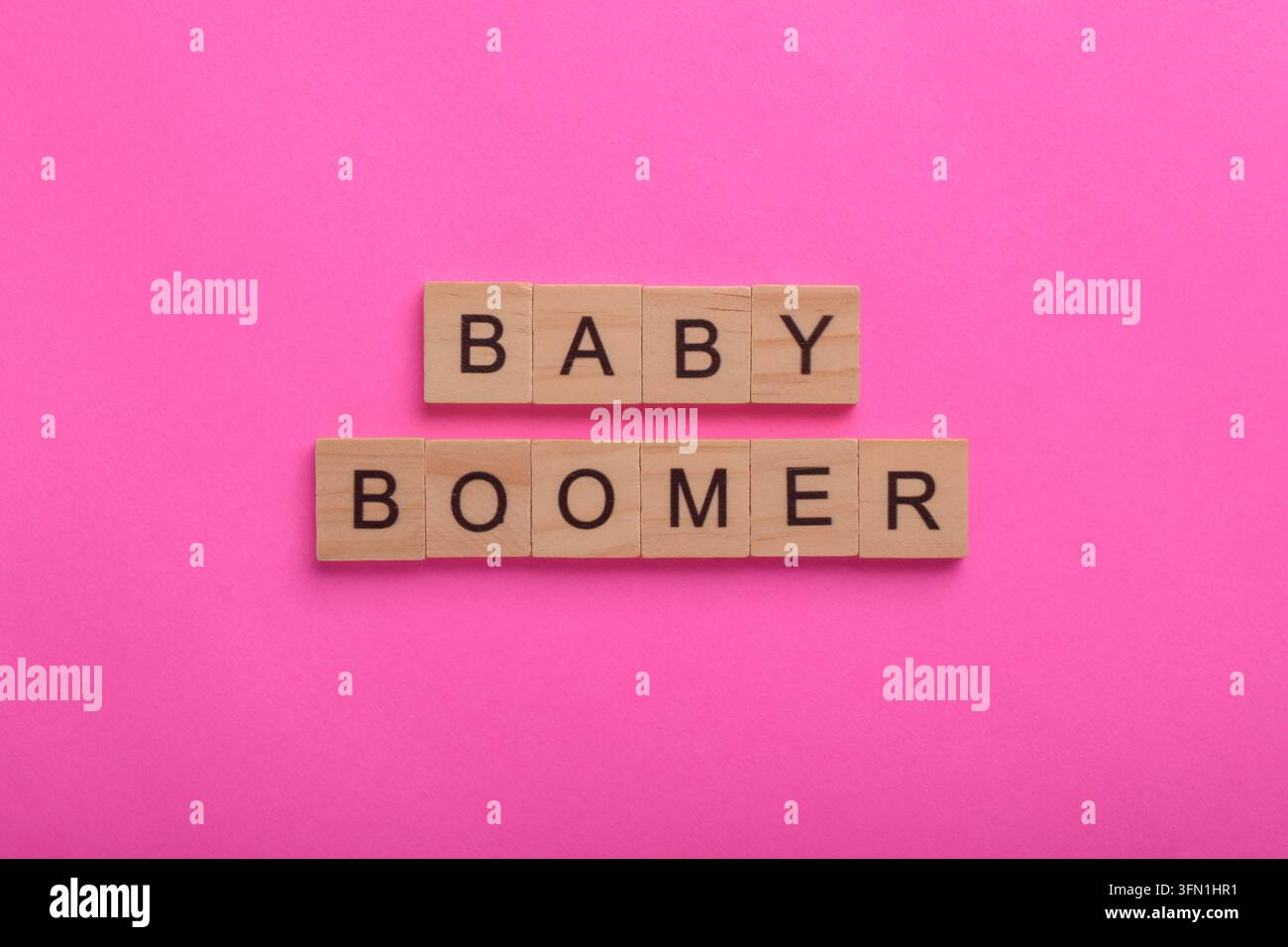 Blocchi di legno con lettere che compongono Baby Boomer su uno sfondo rosa, rappresentanti la generazione del dopoguerra, la demografia, l'invecchiamento della popolazione, le tendenze dei consumatori Foto Stock