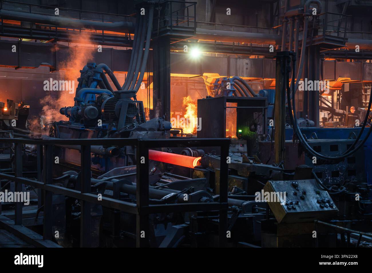 Tubo d'acciaio luminoso passa attraverso una macchina di laminazione a caldo sulla linea di produzione di tubi per la lavorazione metallurgica. Foto Stock