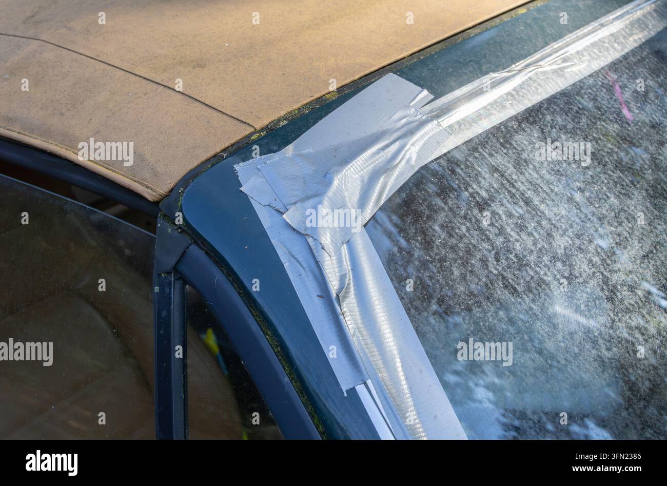 Nastro adesivo sigilla il parabrezza anteriore di un'auto per prevenire perdite d'acqua Foto Stock