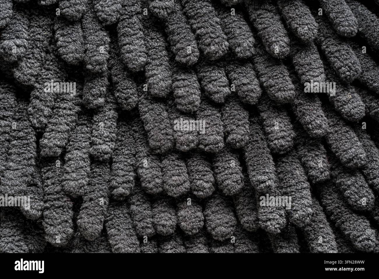 Texture macro di sfondo in tessuto microfibra chenille nera. Fibre di tappeto chenille grigio scuro e morbido. Sfondo texture in materiale tessile accogliente per la casa Foto Stock