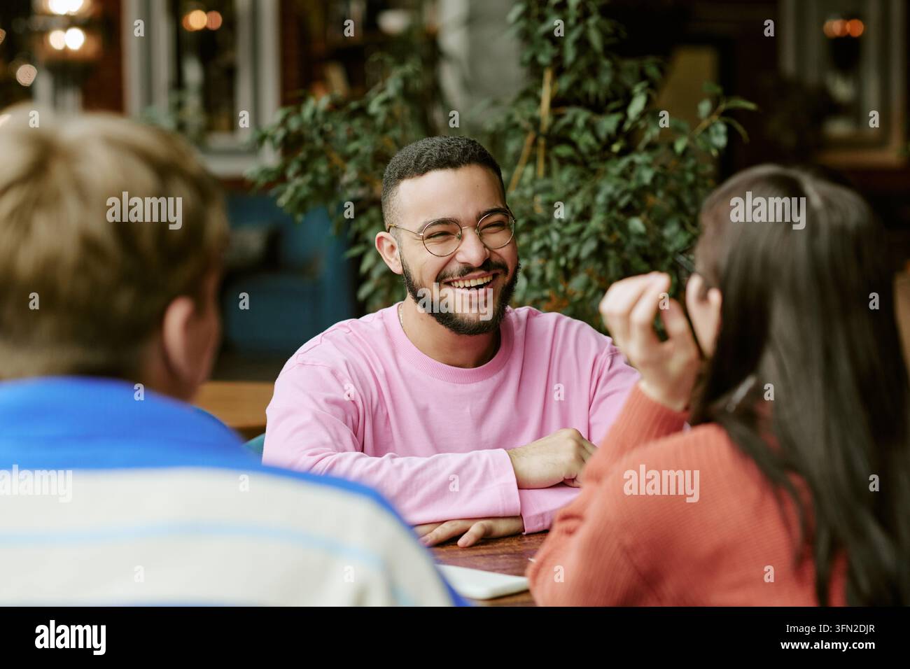 Amici diversificati felici che conversano e ridono in un caffè moderno Foto Stock