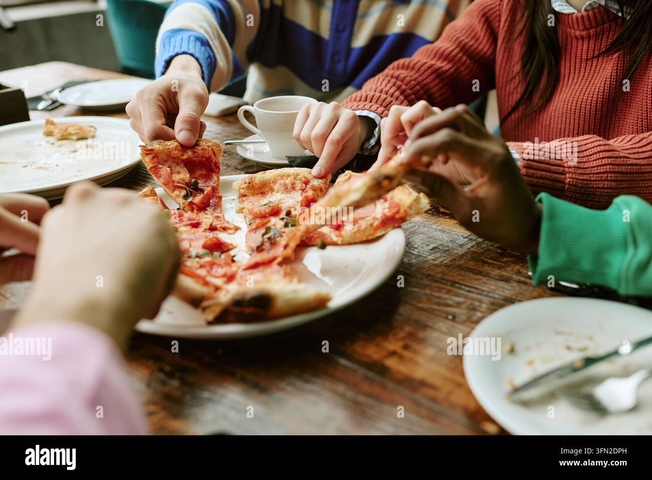 Gruppo multietnico di amici che condividono la pizza a un tavolo da ristorante Foto Stock