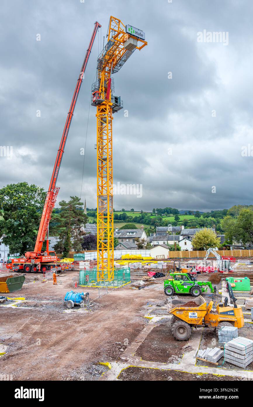 Macchinari pesanti e attrezzature edili al lavoro su un progetto di edificio residenziale a più piani nella città gallese di Brecon. Foto Stock