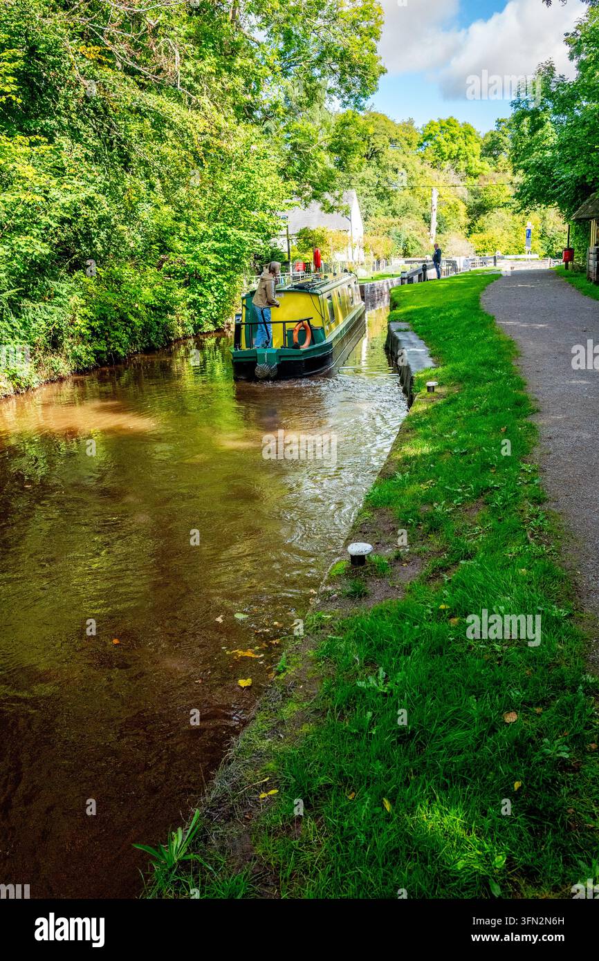 La suggestiva via navigabile presenta un'imbarcazione tradizionale che naviga attraverso la campagna con un sentiero ghiaioso che corre lungo l'acqua tranquilla Foto Stock