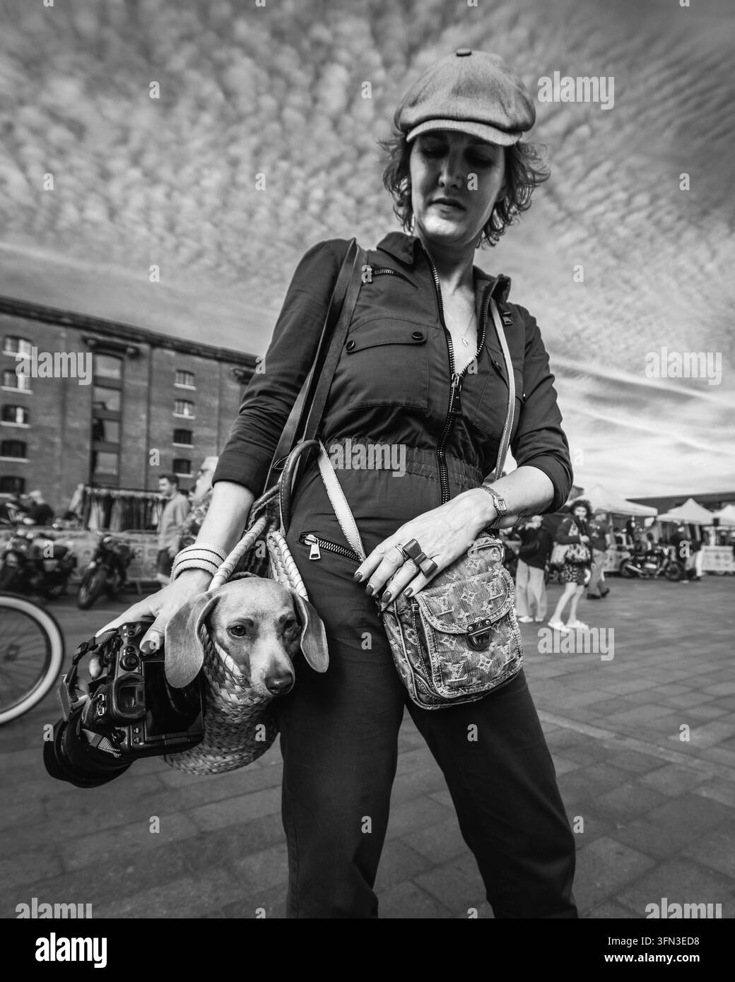Un'immagine in bianco e nero di un cagnolino in una borsa e del suo proprietario fotografo al mercatino vintage di Londra. Foto Stock