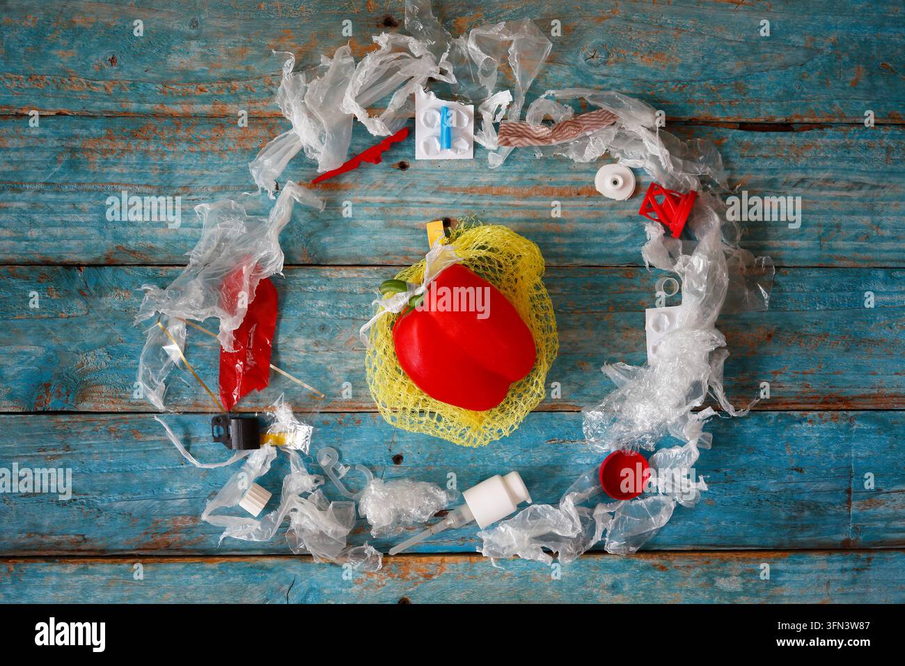 Inquinamento di verdure e altri alimenti con microplastica, peperone singolo circondato da rifiuti di plastica, primo piano, spazio libero per la copia Foto Stock