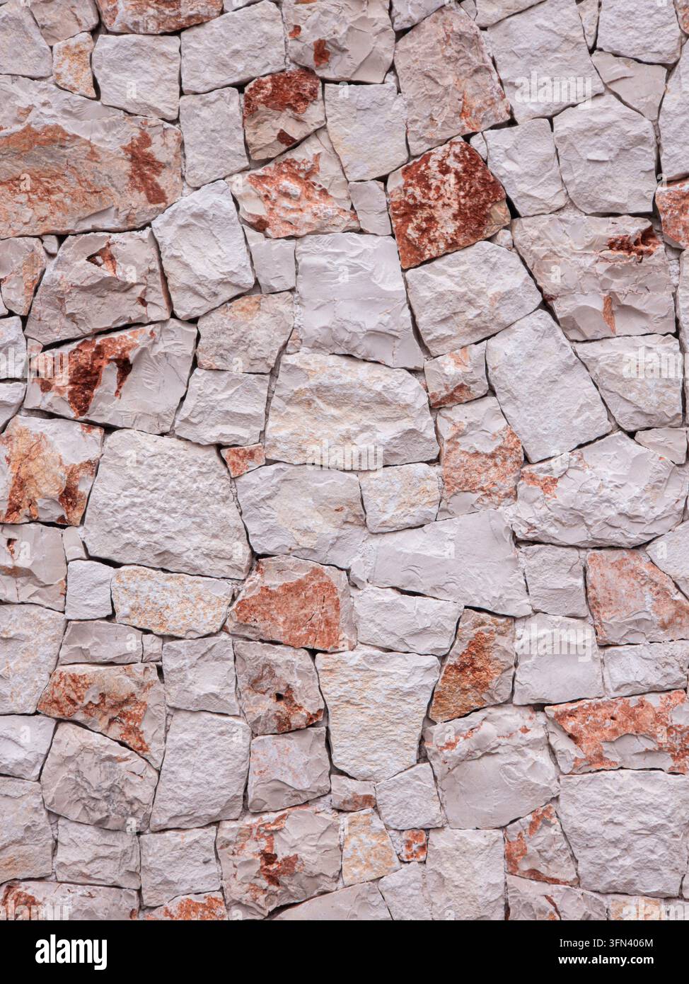 La scena mostra una trama di sfondo senza giunzioni di un muro in blocco di calcare. Il muro è composto da pietre ruvide beige e rossastre. Foto Stock