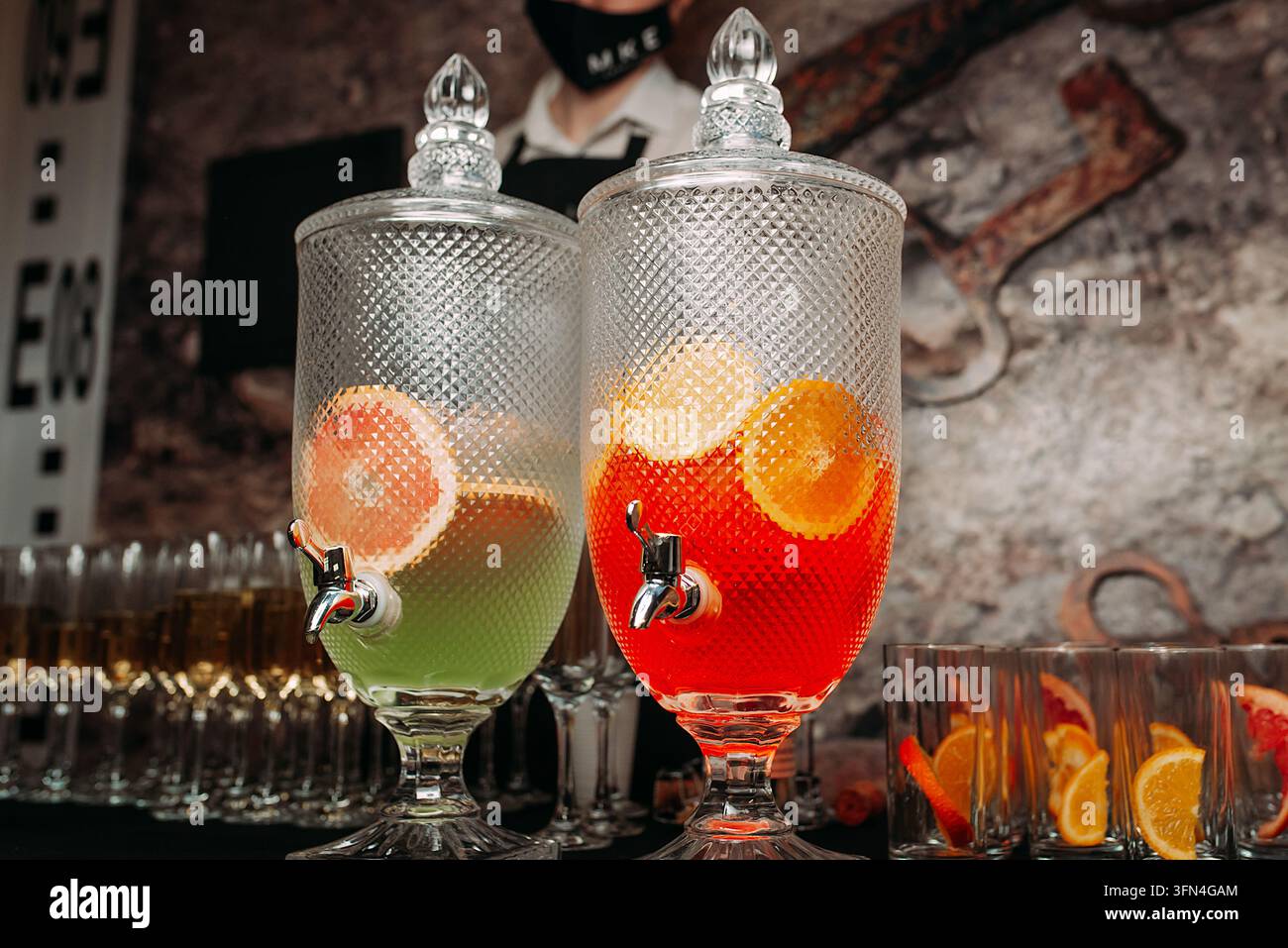 Bevande colorate agli agrumi in dispenser di vetro a una festa Foto Stock