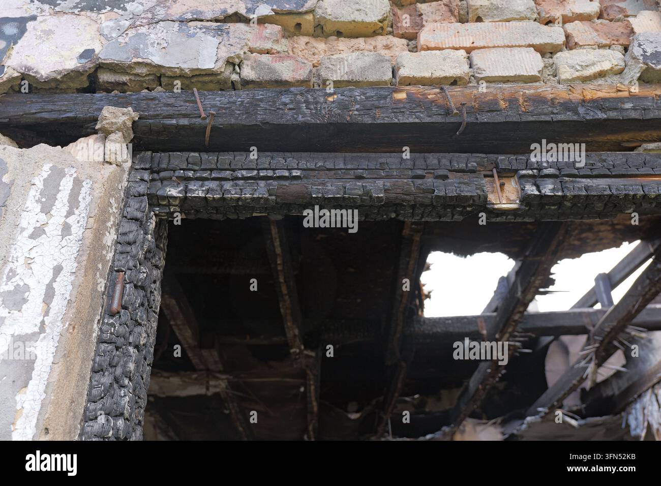 Travi di legno bruciate e muratura carbonizzata rivelano una struttura residenziale devastata dopo un incendio, mostrando muri distrutti, struttura esposta e il netto a Foto Stock