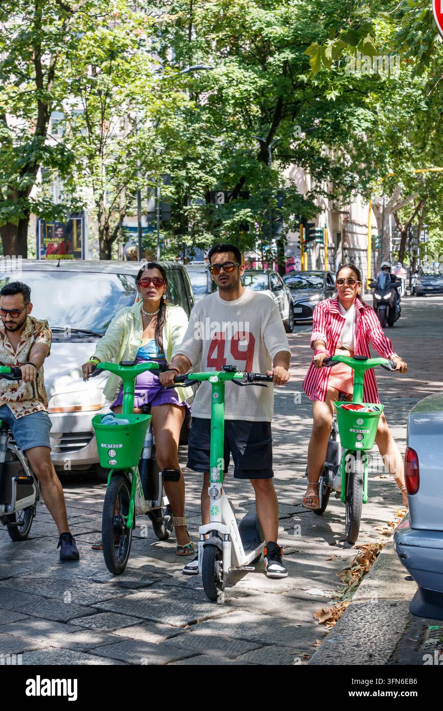 Persone in sella a scooter elettrici Lime e biciclette Lime su una strada in Europa Foto Stock