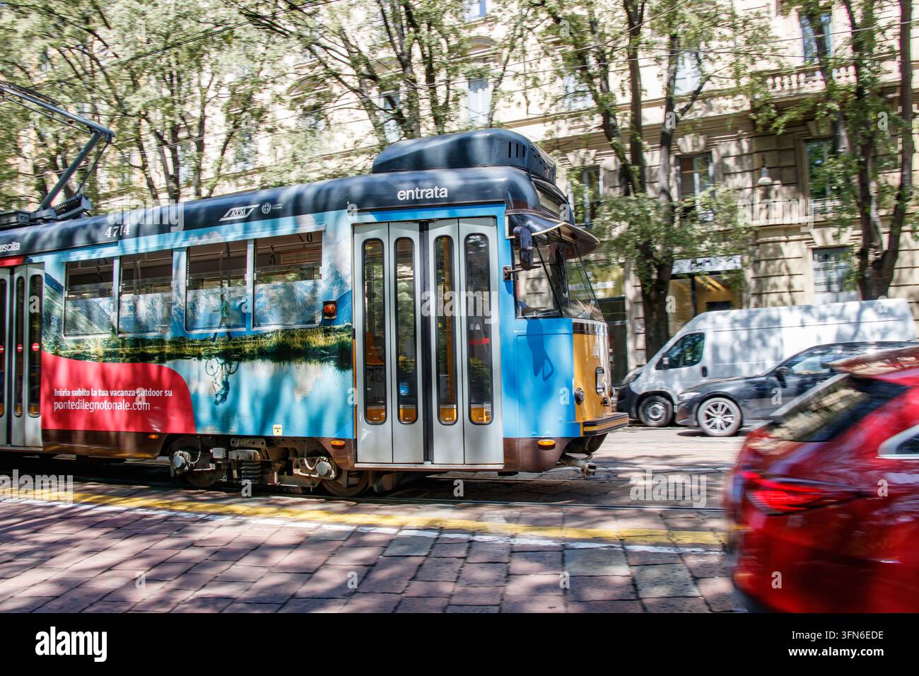 Tram giallo e blu 1711 dell'ATM che corre lungo il binario della strada a Milano, Italia Foto Stock