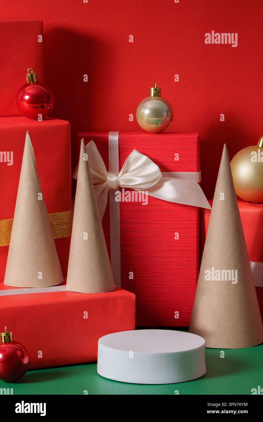 Mockup minimalista di podio natalizio con regali rossi e coni di albero su sfondo rosso Foto Stock