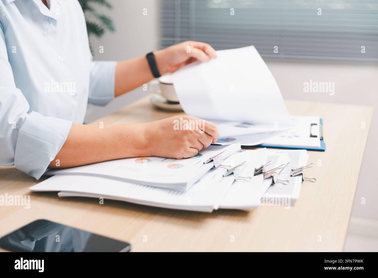 Impiegato d'ufficio che smista rapporti finanziari e documenti su una scrivania, mostrando revisione di documenti, contabilità, analisi aziendale, budgetazione, amministrazione, da Foto Stock