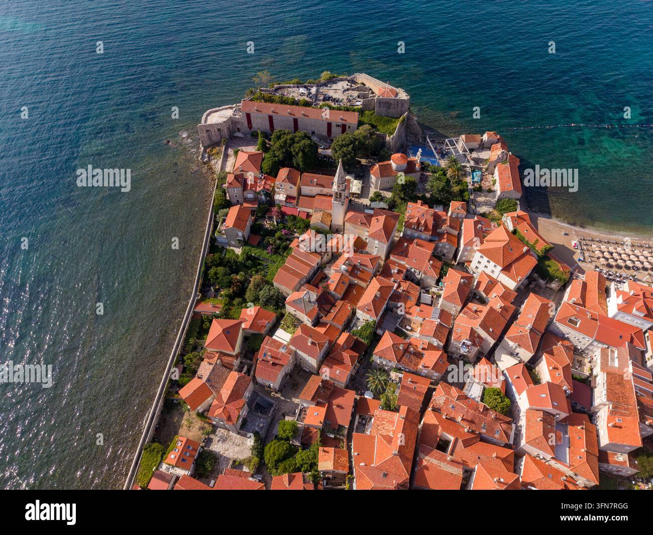 La vecchia città di Budva in Montenegro occupa una penisola fortificata accanto al mare Adriatico, con tetti di terracotta fitti e edifici in pietra. Architettura costiera un Foto Stock