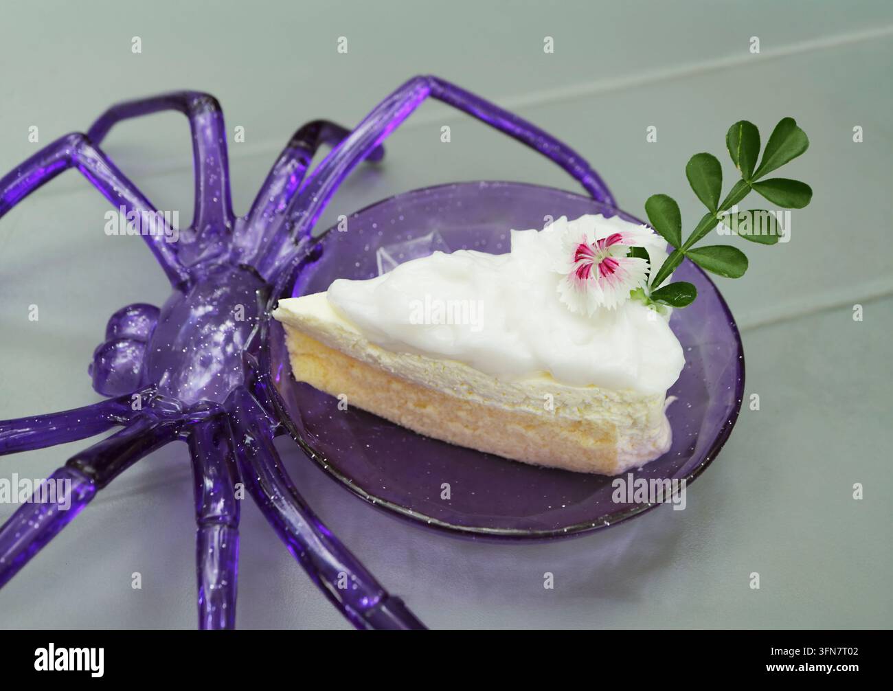 Delizioso chiffon cake al cocco giovane di Halloween con glassa bianca servito su un piatto viola a forma di ragno Foto Stock