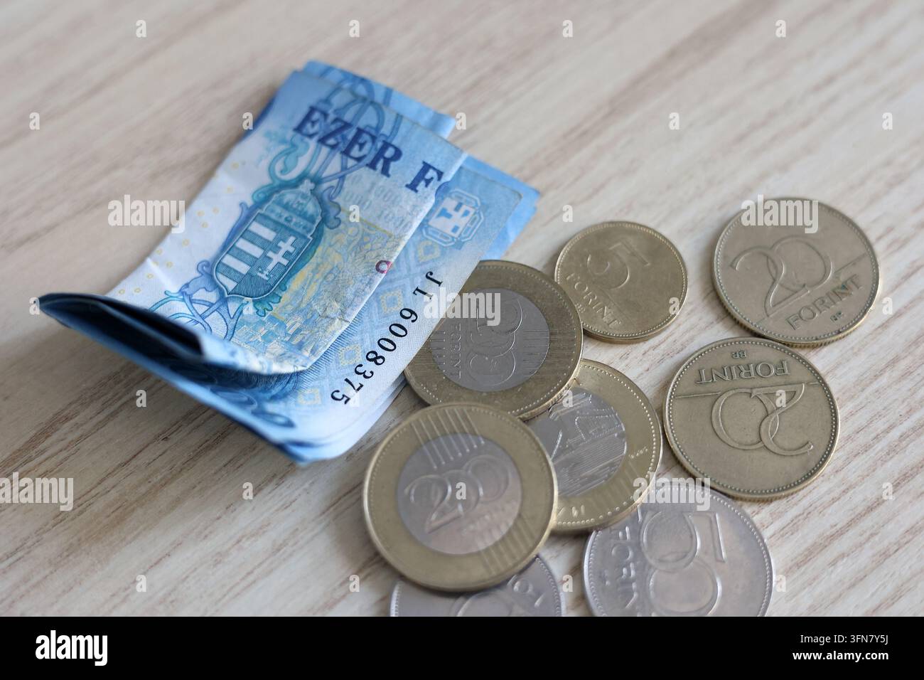 Banconote e monete in fiorino ungherese sparse su una superficie di legno Foto Stock
