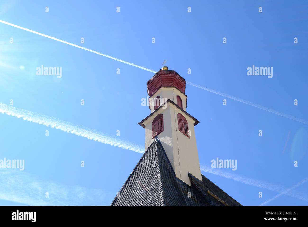 Torre di chiesa storica con tetto rosso contro un cielo blu terso. Foto Stock