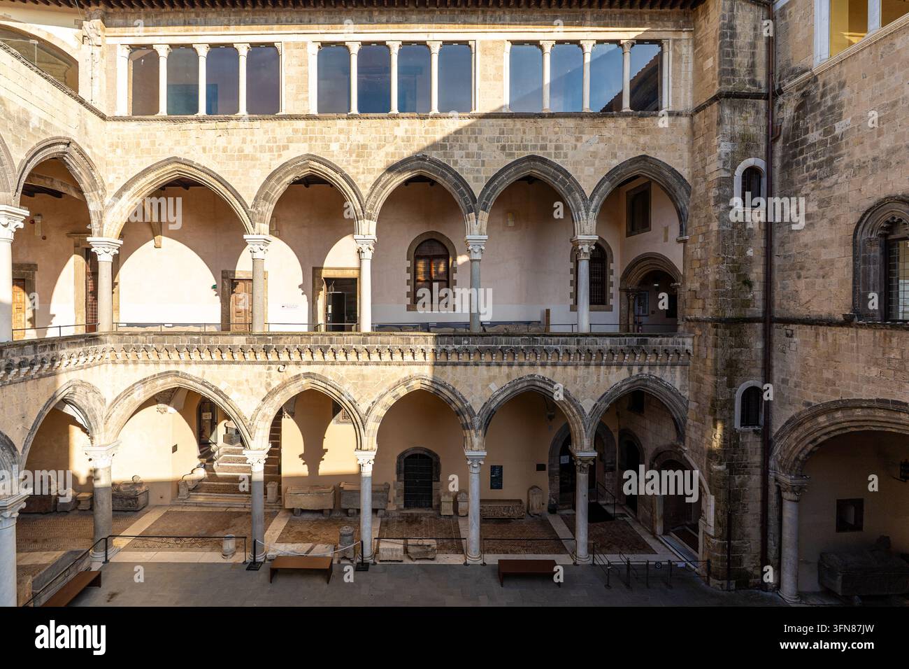 Un'inquadratura frontale e simmetrica che mostra la magnifica struttura architettonica del cortile interno disposta su tre livelli distinti. La gr Foto Stock