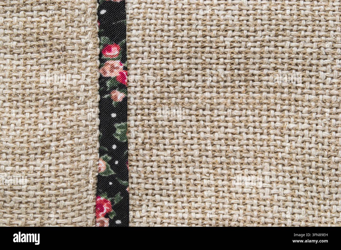 Tessuto di tela beige con stampa floreale, nastro nero in primo piano come sfondo Foto Stock