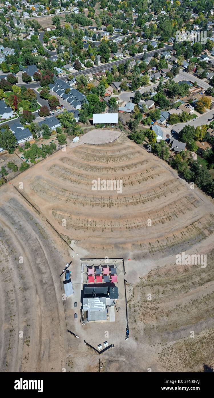 Veduta aerea del drive-in con il suo grande schermo, le file di parcheggio curve e il quartiere residenziale circostante a Fort Collins, Colorado, Un Foto Stock