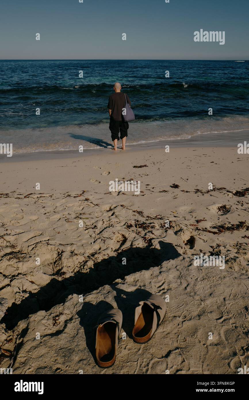 Sandali di pelle in primo piano con un uomo a piedi nudi in piedi Foto Stock