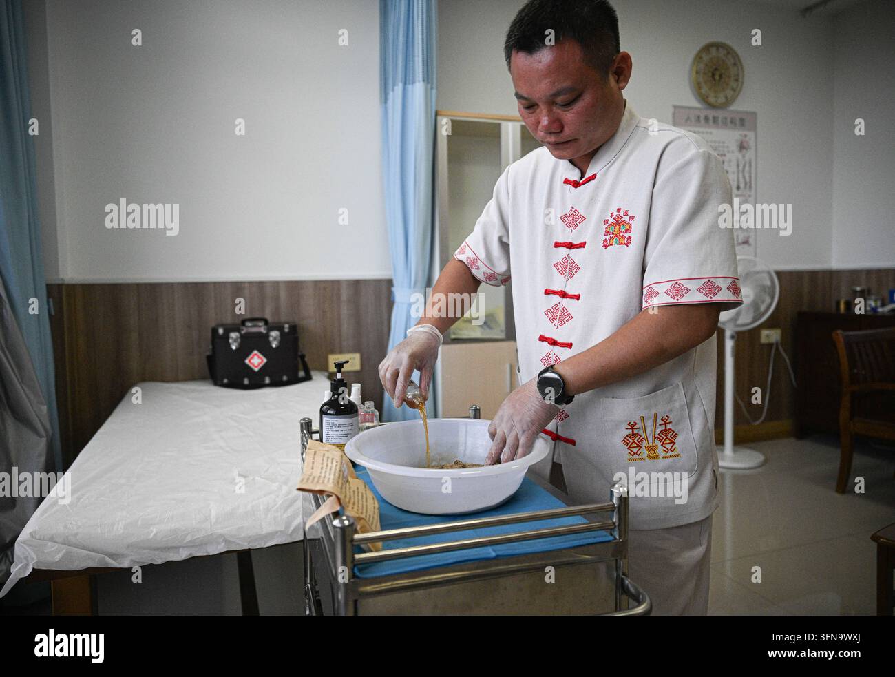 (261002) -- BAOTING, 2 ott. 2026 (Xinhua) -- Wang Haicong, erede della medicina Li, prepara la medicina Li in un ospedale di medicina Li nella contea autonoma Li e Miao di Baoting, nella provincia meridionale cinese di Hainan, il 30 settembre 2026. La medicina Li, inclusa la terapia delle lesioni ossee e il trattamento dei morsi di serpente, è riconosciuta come patrimonio culturale immateriale rappresentativo a livello provinciale nella provincia di Hainan. L’ospedale di medicina Li di Baoting è stato inaugurato nel 2024. Prima di ciò, le pratiche mediche Li erano disperse nelle aree urbane e rurali. L’ospedale raccoglie gli eredi della medicina Li e sfrutta th Foto Stock