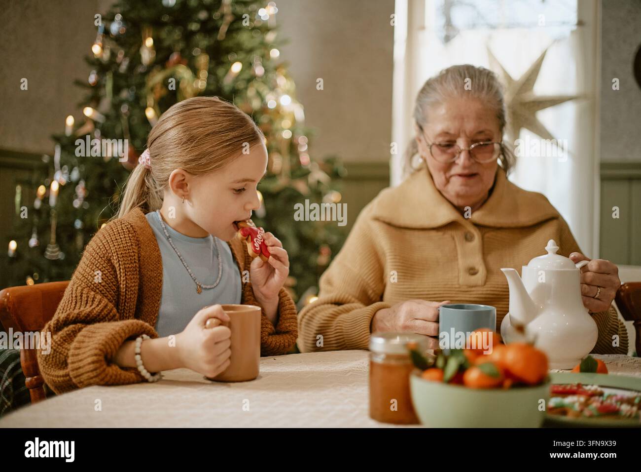 Anziana con nipote che beve tè a Natale Foto Stock