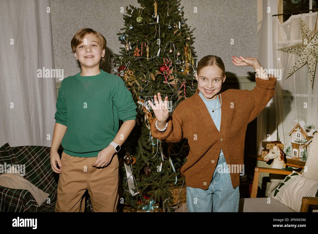 Ritratto di bambini allegri che ballano vicino all'albero di Natale Foto Stock