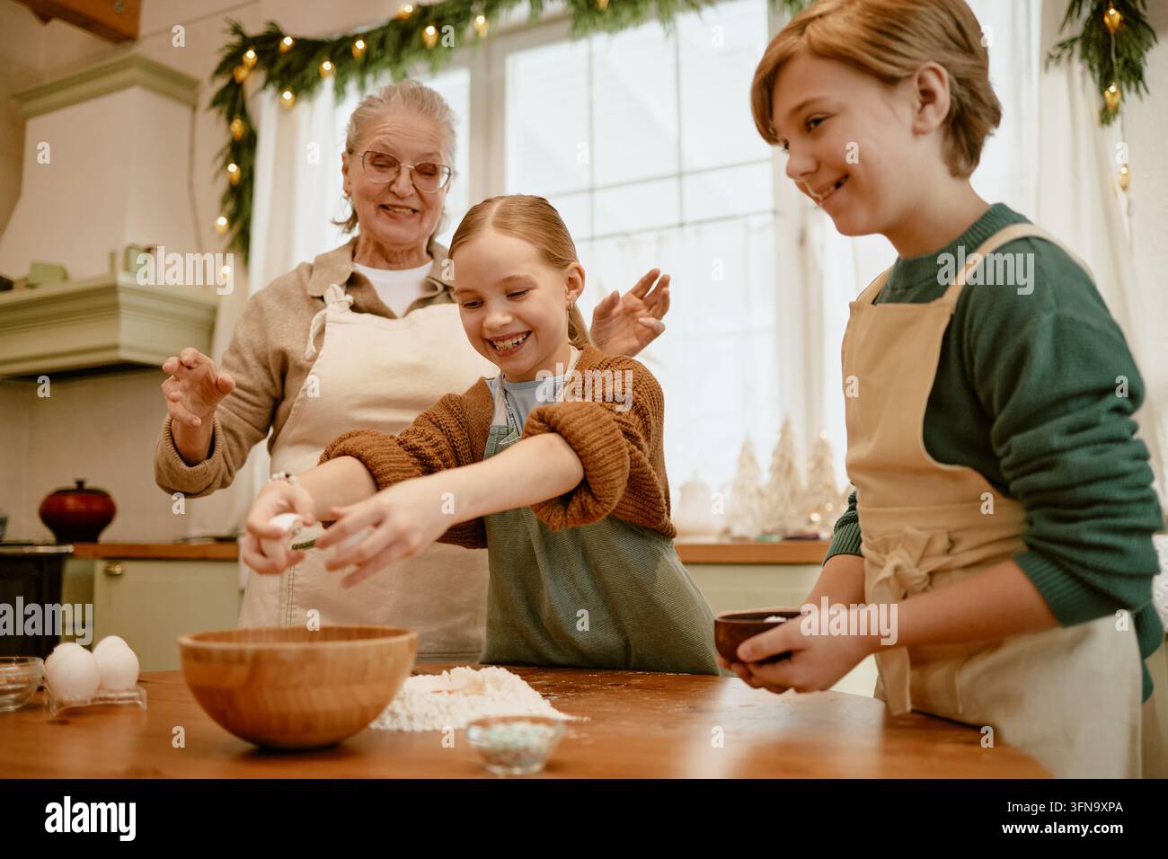 Donna anziana che prepara dolci con i bambini durante i preparativi per le feste Foto Stock