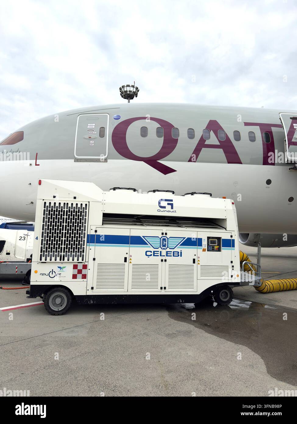 Aereo passeggero di Qatar Airways parcheggiato sulla pista con un'unità di alimentazione a terra attaccata Foto Stock