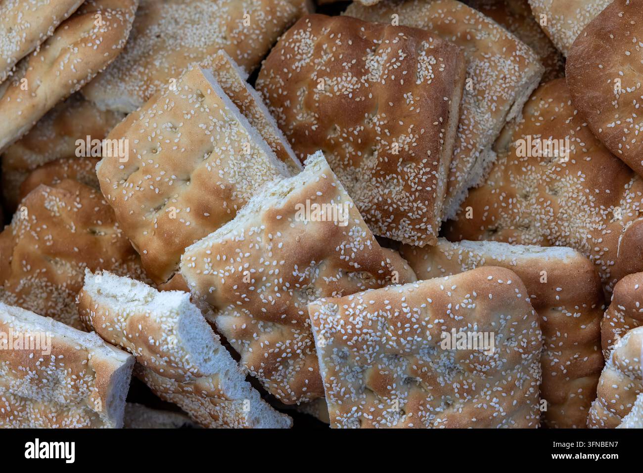 Pane tradizionale greco lagana appena sfornato coperto di semi di sesamo, esposto a una bancarella di pasticceria durante la stagione delle festività a Salonicco, Grecia. Foto Stock