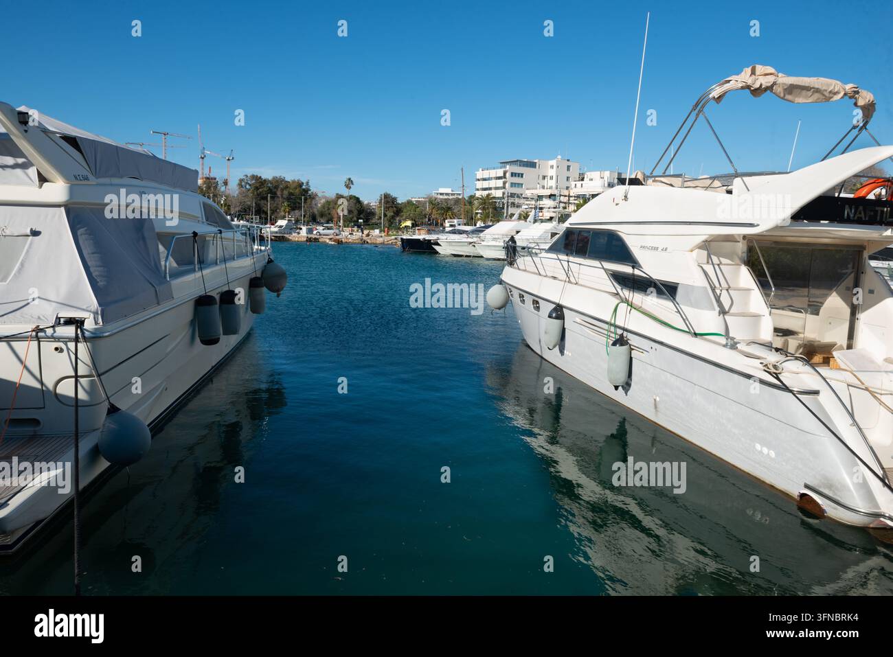ATENE, GRECIA - 19 FEBBRAIO 2026: Yacht a motore di lusso bianchi ormeggiati lungo il bacino calmo della marina di Glyfada sulla Riviera ateniese nella Grande Atene Foto Stock