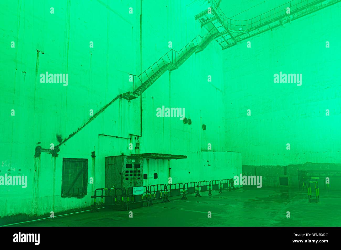 Mura di cemento e strutture industriali immerse nella luce verde all'interno della centrale nucleare sotterranea 816 a Fuling, Chongqing, Cina Foto Stock