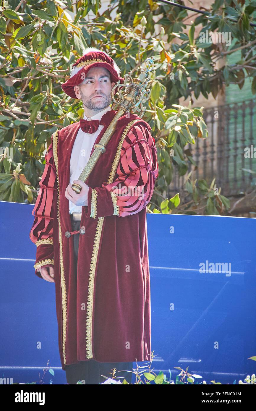 Ricreatore storico in costume bordeaux che tiene un bastone cerimoniale ornato al festival Capitulaciones de Santa Fe Foto Stock