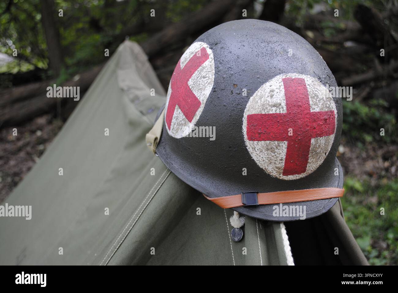 Casco di un medico della Seconda Guerra Mondiale con segni della croce rossa appoggiato su una tenda di tela durante una rievocazione storica a Rockford, Illinois. Foto Stock