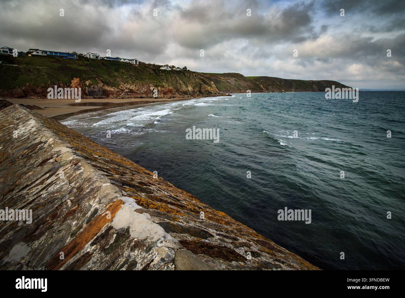 Muro portuale di pietra e spiaggia a Gorran Haven, Cornovaglia, Inghilterra Foto Stock