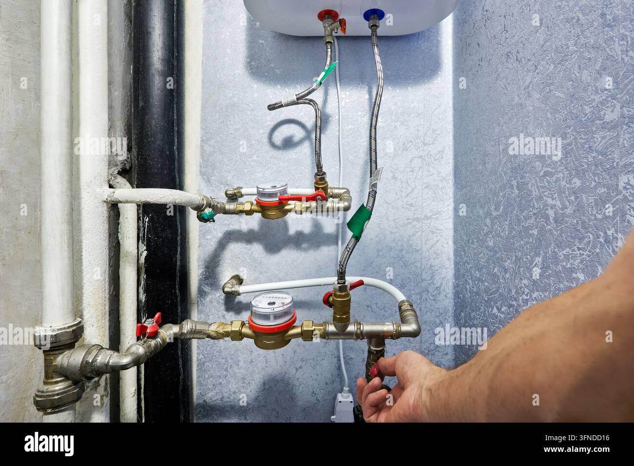 Installazione di un insieme contamisure dell'acqua e di un collettore idraulico su una parete interna durante la manutenzione della configurazione idraulica residenziale Foto Stock