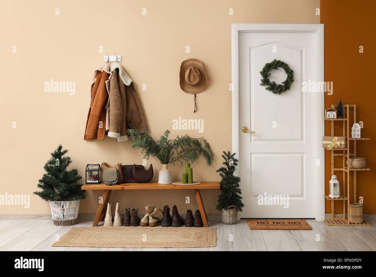 Design degli interni e preparazione delle vacanze, ingresso accogliente con cappotti invernali e decorazioni natalizie nel corridoio di una casa moderna Foto Stock