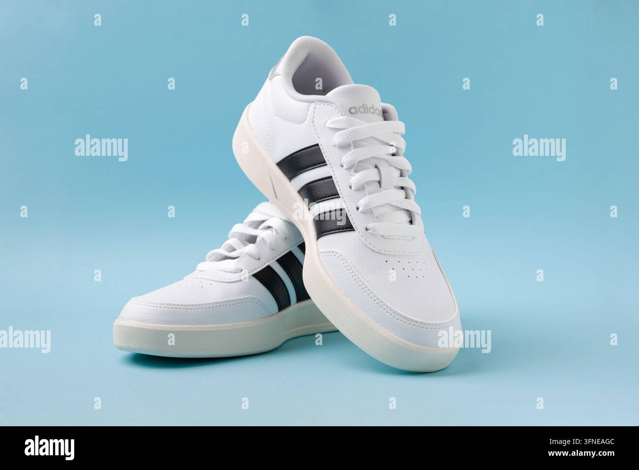 Antalya, Turchia – 2 settembre 2026: Sneaker bianche Adidas Breaknet 3.0 con strisce nere disposte su sfondo blu in studio Foto Stock