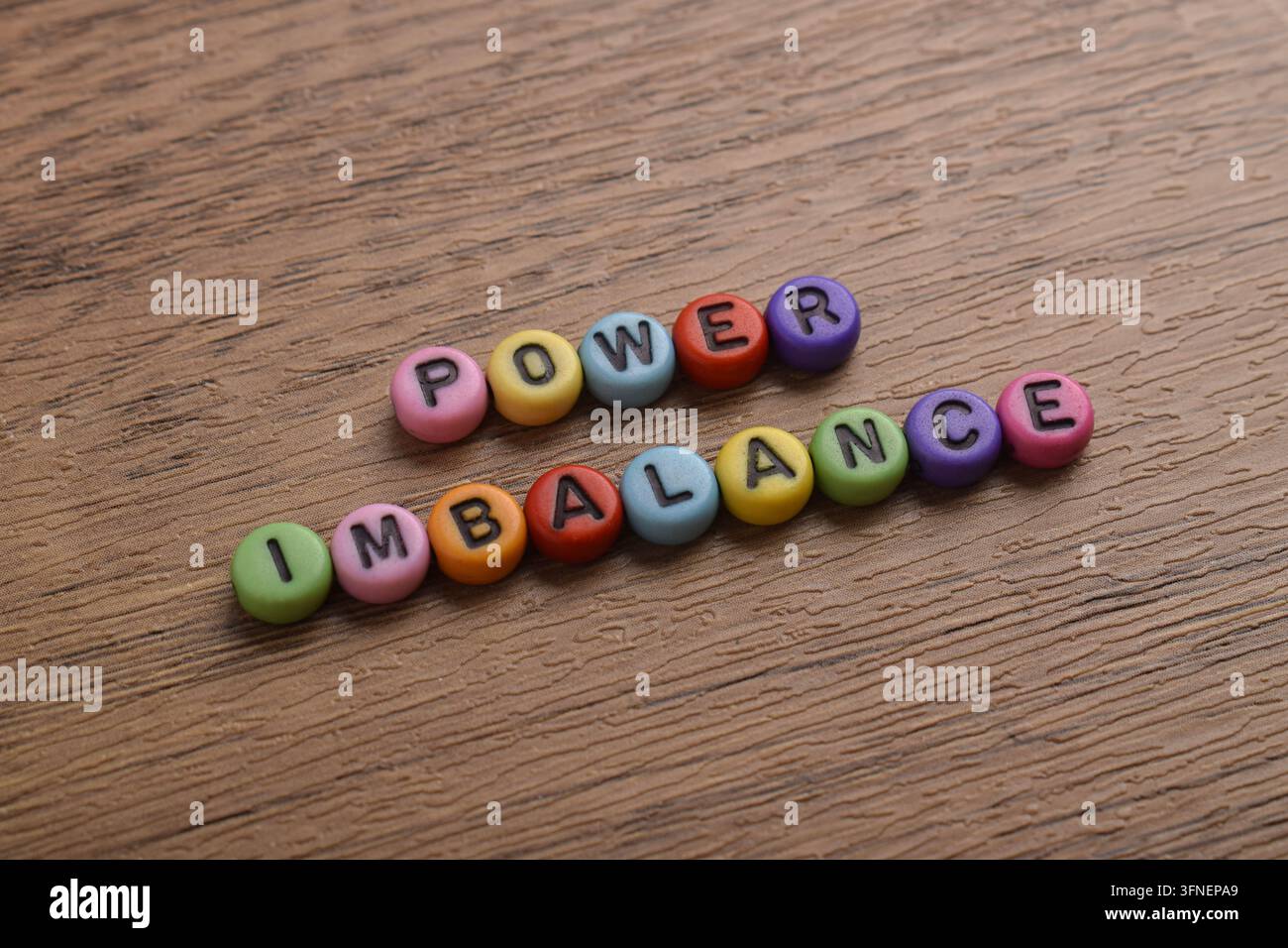 Perle di lettere colorate che compongono Power Imbalance su una superficie di legno, rappresentando autorità disuguale, gerarchia sul posto di lavoro, disuguaglianza sociale, leadership Foto Stock