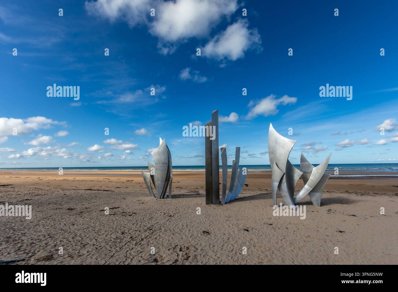 Sculture metalliche astratte dai bordi taglienti che riposano sulla spiaggia sabbiosa sotto la luce soffusa e diffusa dell'ora blu. Foto Stock
