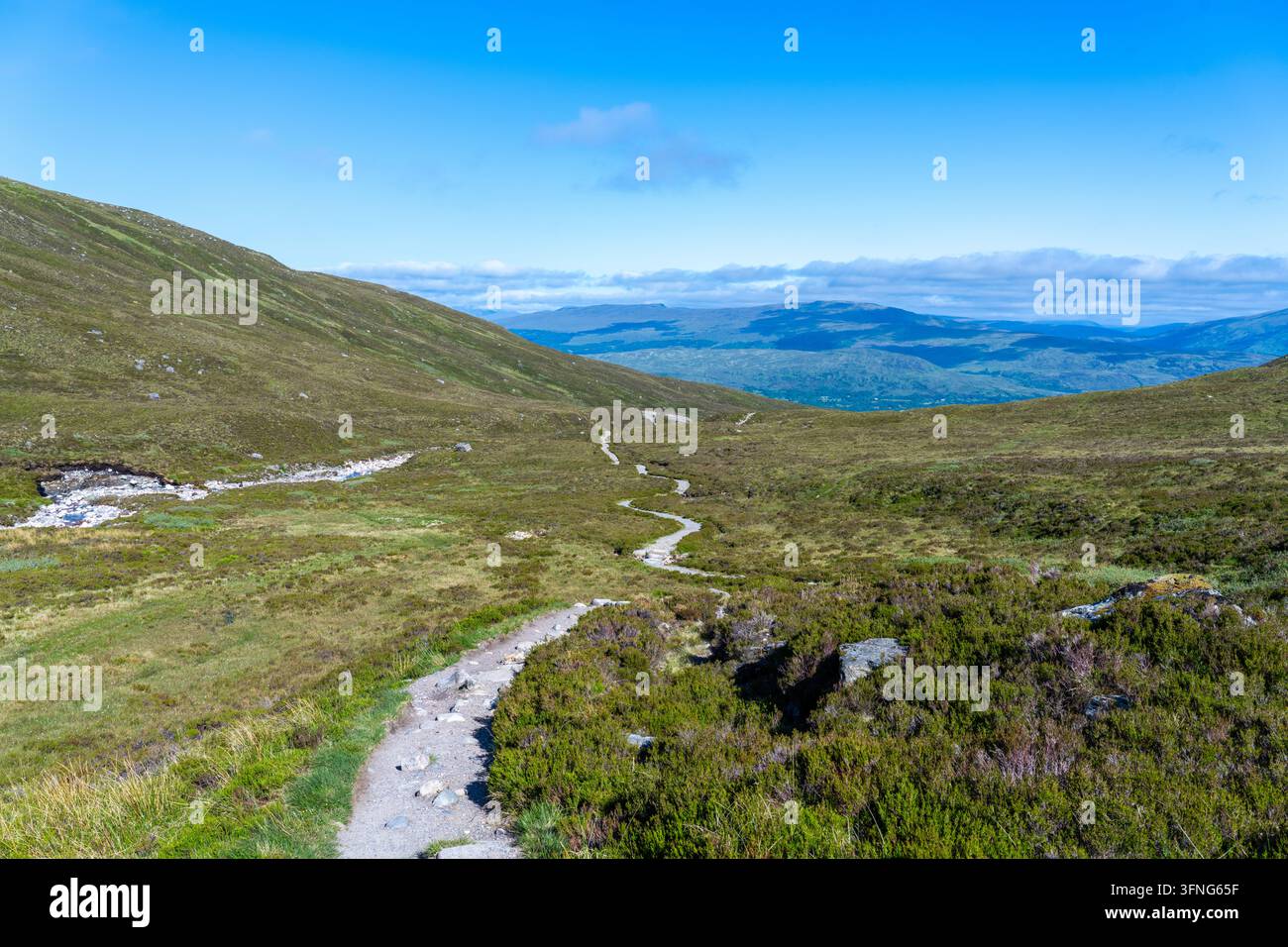 Un sentiero escursionistico che scende una montagna nelle Highlands scozzesi con alcune vedute su un'altra catena montuosa Foto Stock