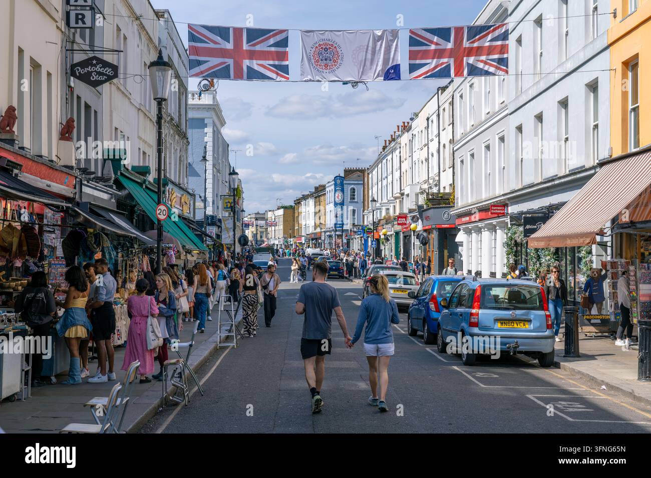 Londra Inghilterra - 28 maggio 2023: Una coppia che si tiene per mano mentre cammina lungo Portobello Road a Notting Hill in Inghilterra con molti negozi Foto Stock