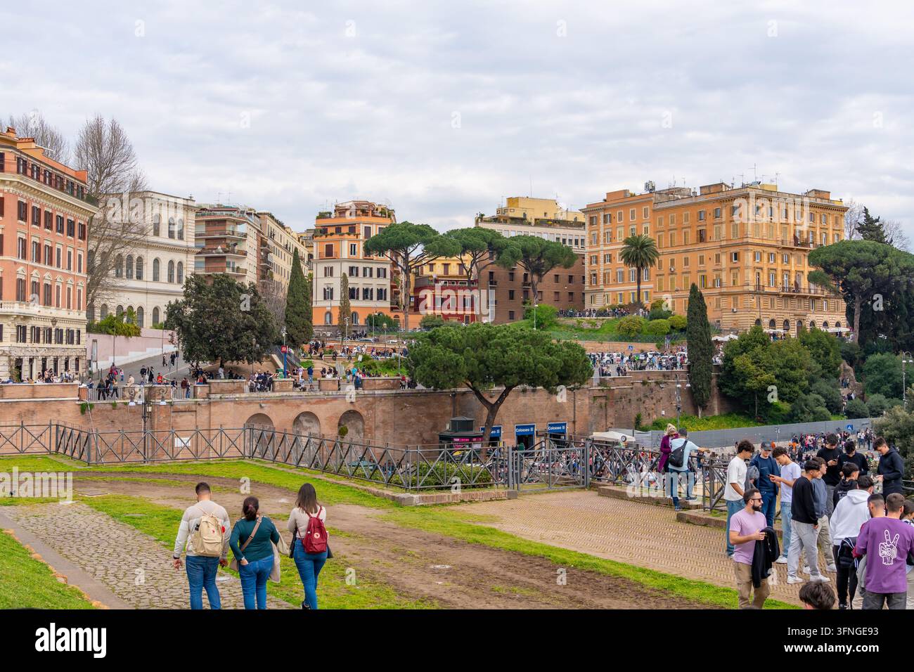 Roma, Italia - 09 marzo 2025: Una scena vivace a Roma con edifici storici, alberi rigogliosi e pedoni che passeggiano lungo una promenade scenografica Foto Stock