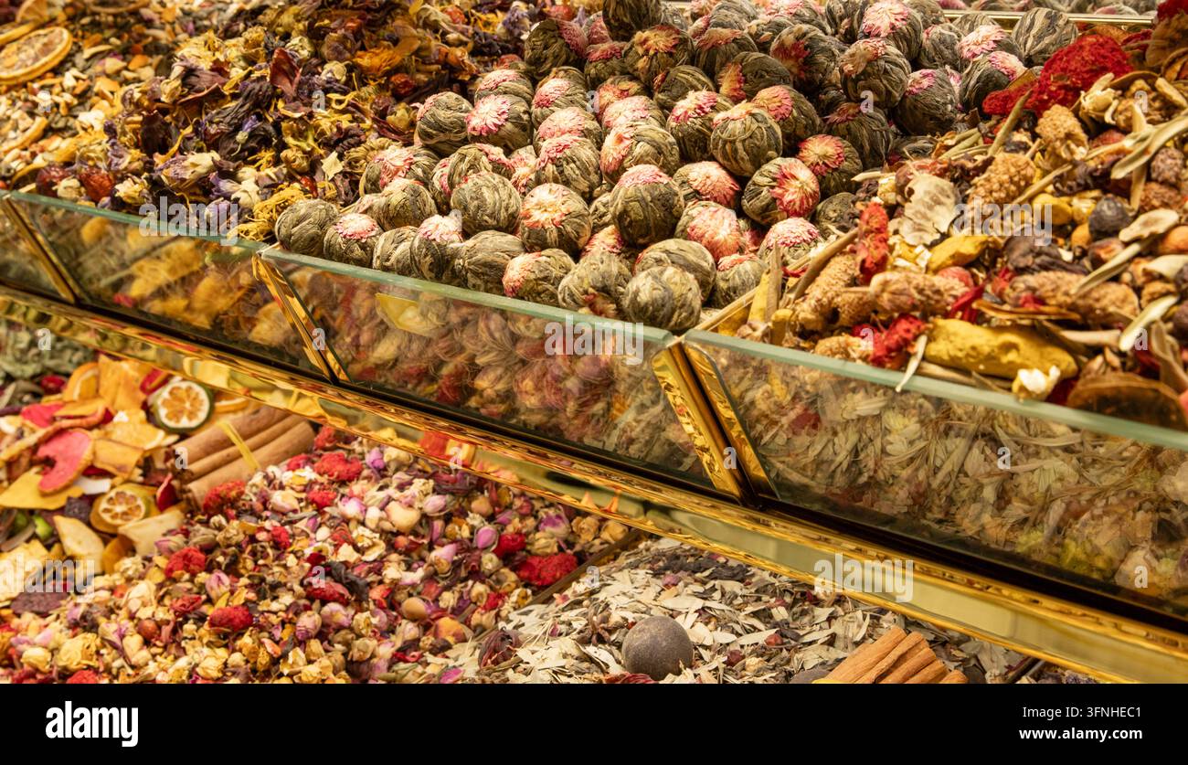 Sfere di tè fiorite e miscele di erbe esposte in contenitori di mercato di vetro Foto Stock