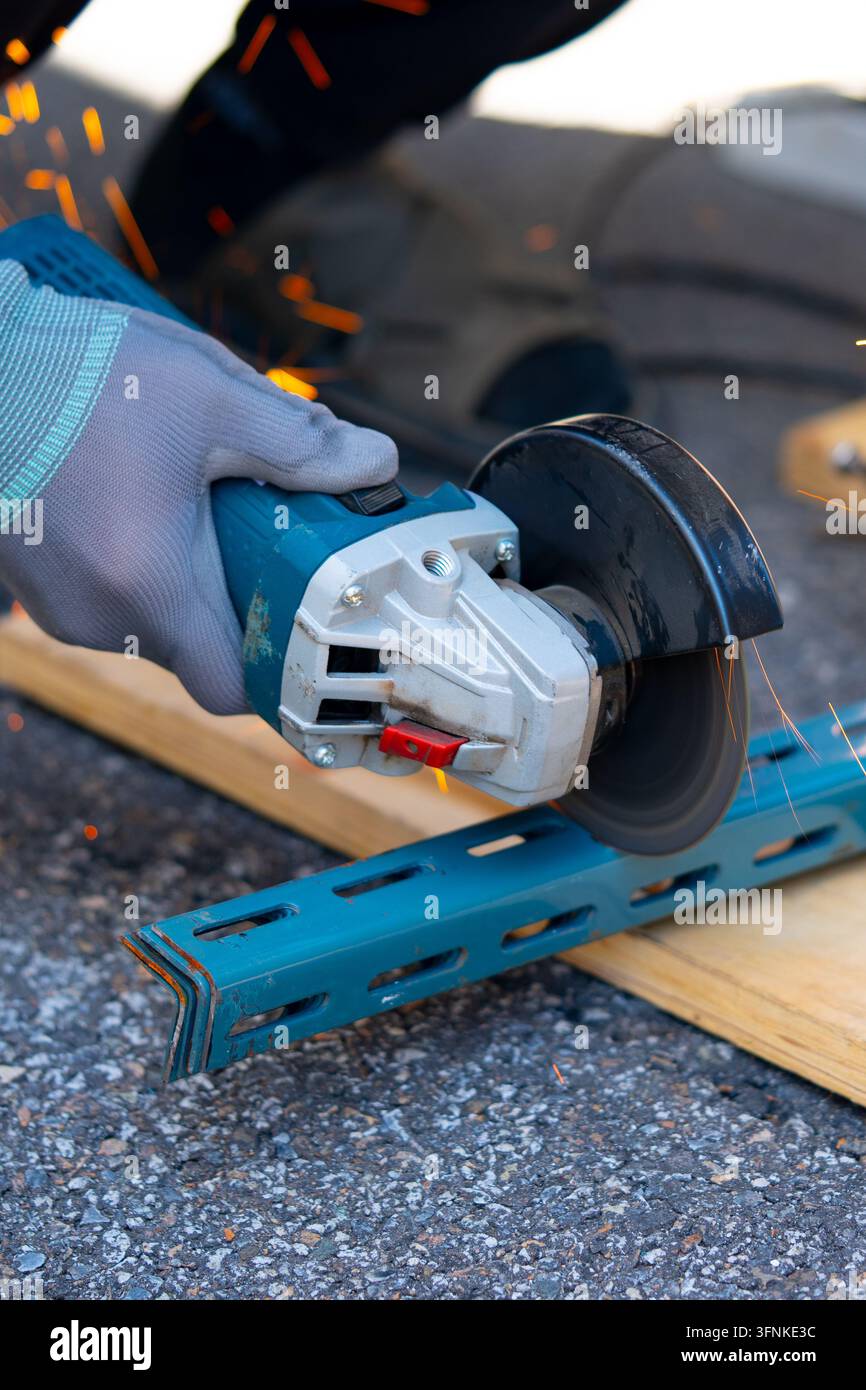 Operaio che taglia il metallo con molte scintille affilate utilizzando attrezzature per tagliare il ferro Foto Stock