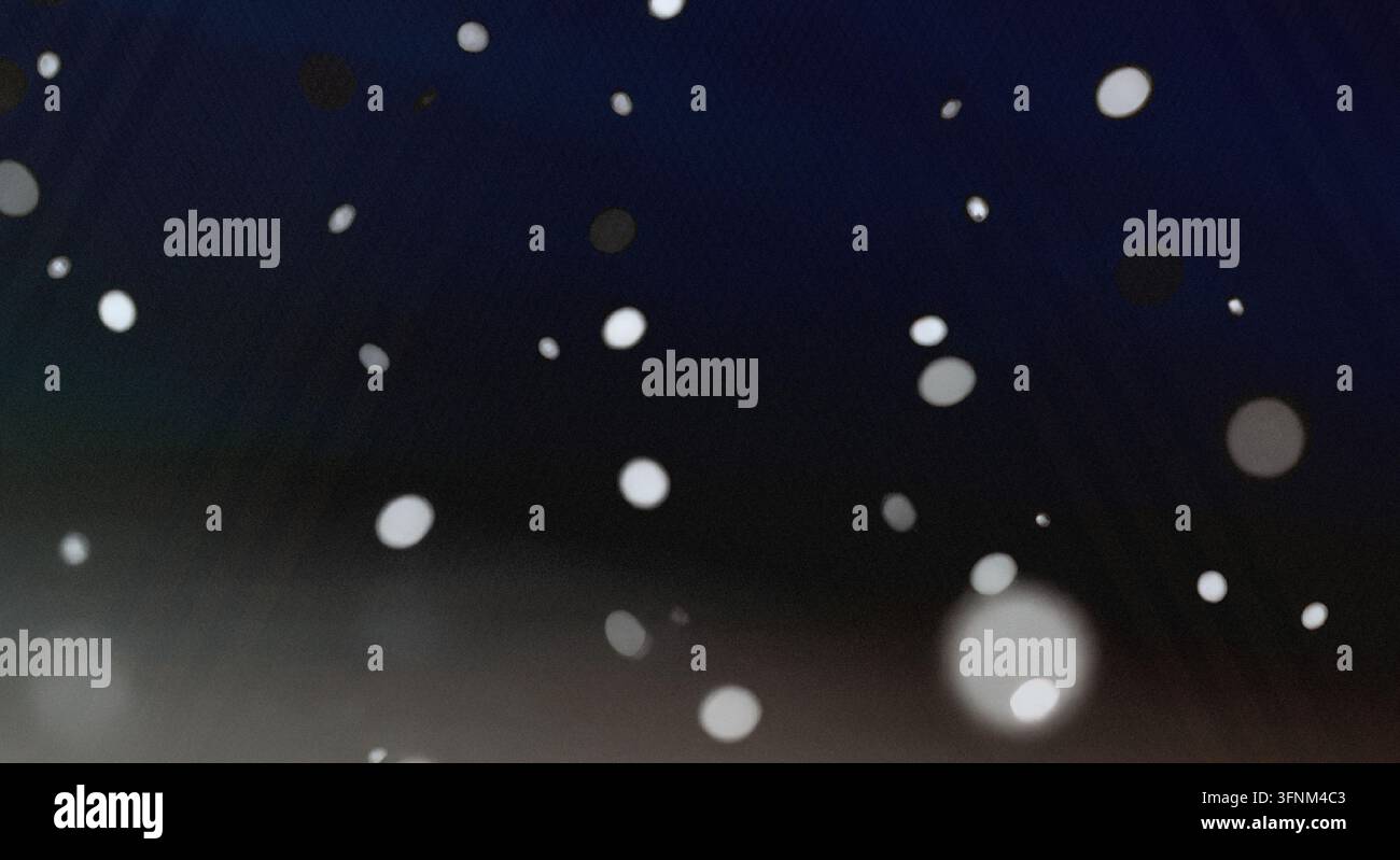 Una composizione artistica di punti bokeh bianchi luminosi che fluttuano su uno sfondo profondo e scuro, evocando la sensazione di neve che cade o di stelle lontane. Foto Stock