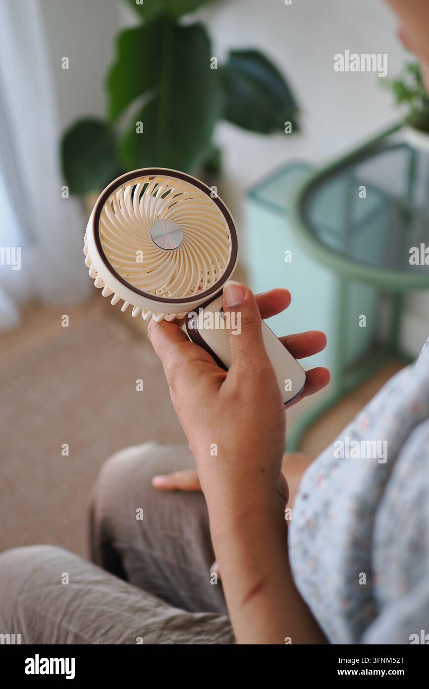 una persona che tiene un mini ventilatore portatile USB manuale Foto Stock